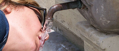 A tourist takes a moment to quench her thirst inside the Vatican.